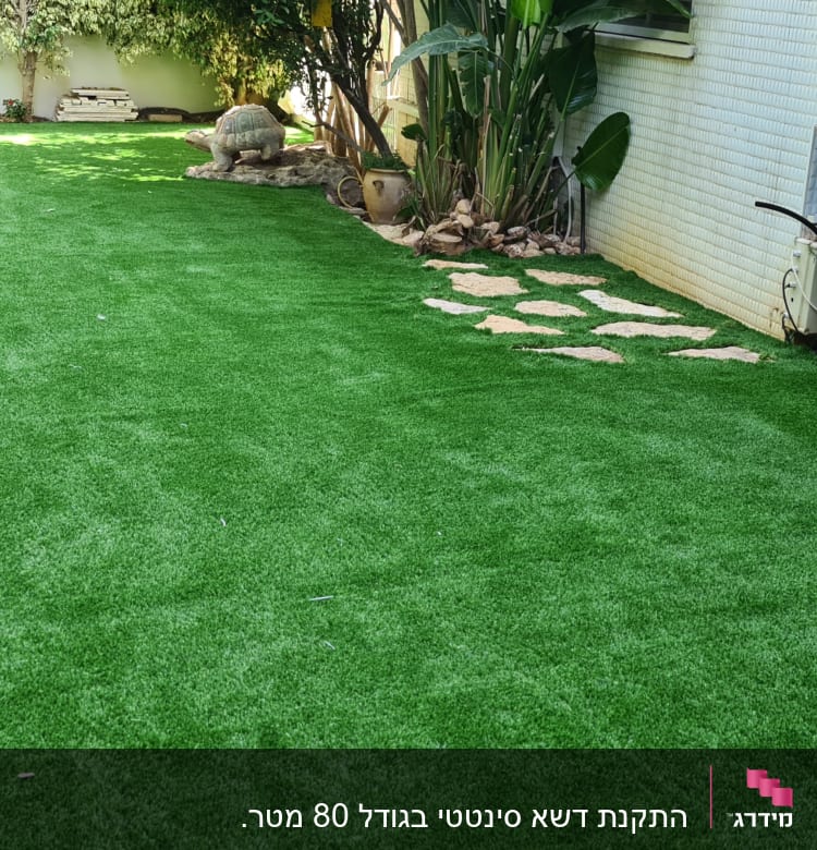 דשא סינתטי עם שביל אבנים ועציצים בצד